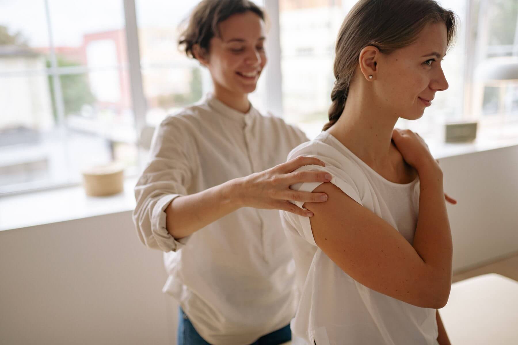 Physiotherapeutin behandelt die Schulter einer Patientin